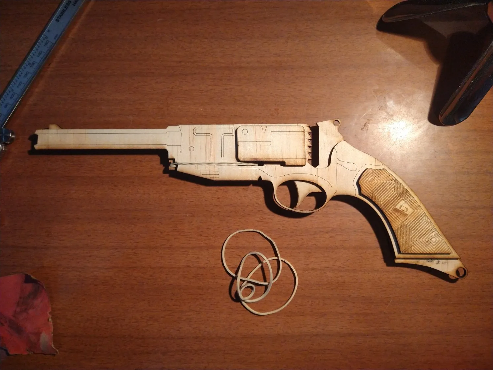 Mal's Revolver, a wooden six-shot elastic band gun, lying on a desk with spare elastic bands